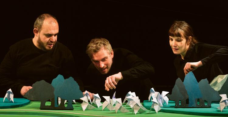 Photo d'une femme et deux hommes jouant avec des cocottes en papier